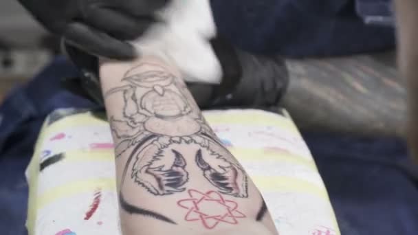 Μια tatooer χρωματισμό tatoo του εντόμου σε επανδρώνει το χέρι — Αρχείο Βίντεο