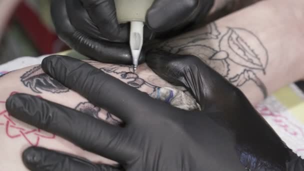 Joven tatuador haciendo tatoo en la mano — Vídeo de stock