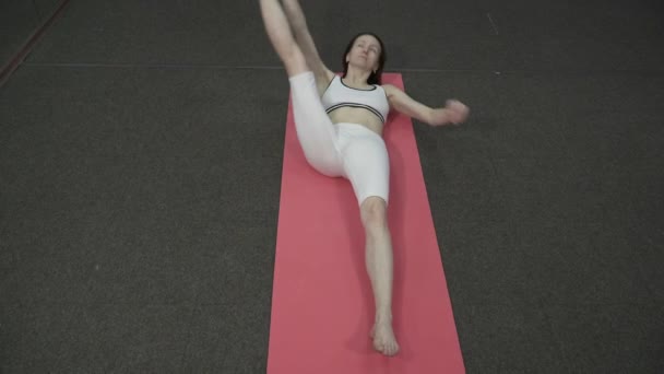 Όμορφη γυναίκα κάνοντας γιόγκα σπονδυλική στροφή πόζα, πόδι προς τα δεξιά — Αρχείο Βίντεο