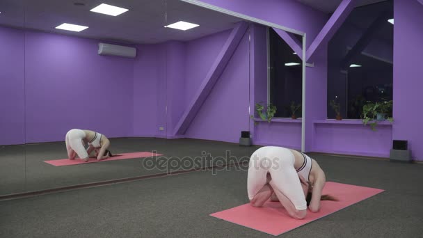 Женщина делает стойку на голове для йоги в позе лотоса перед зеркалом — стоковое видео