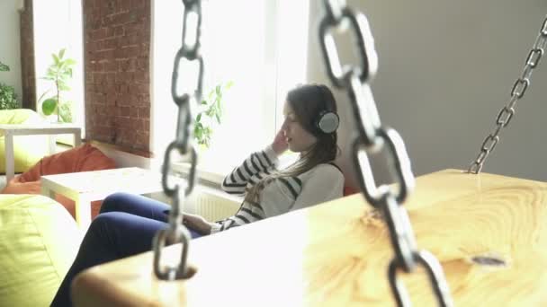 十几岁女孩开心的听音乐，坐在扶手椅上 — 图库视频影像