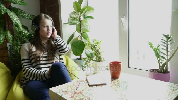 Tinédzser lány lisening zene az ablak mellett — Stock videók