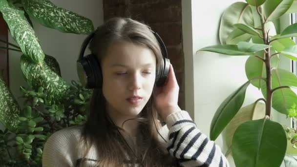 窓の近くの音楽をティーンエイ ジャーの女の子 lisening のクローズ アップ — ストック動画