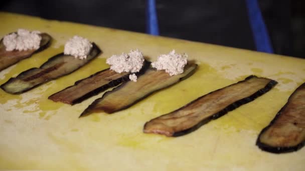 Cocinar sabrosos rollos de berenjena pequeños con queso en el tablero — Vídeo de stock