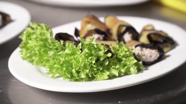 Вкусные маленькие баклажаны с сыром на тарелке с зеленым салатом — стоковое видео