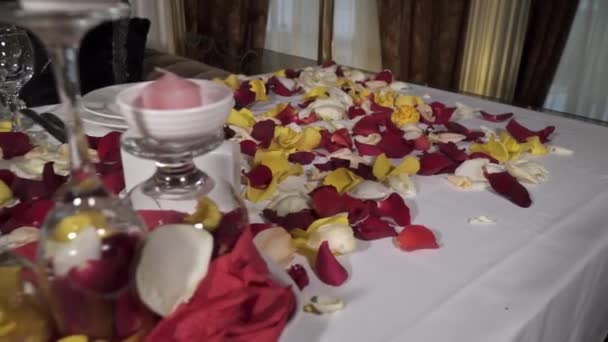 Primer plano de la mesa decorada con pétalos de rosa en el restaurante — Vídeo de stock