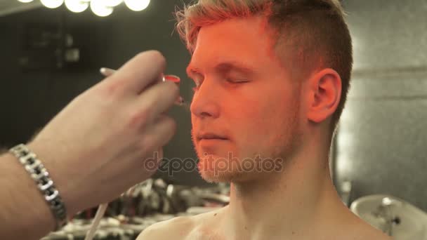 Maquillage maître couvrant le visage des modèles avec des mouvements lents de couleur orange 