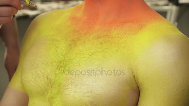 Artista de maquillaje rocía el color en el pecho de los hombres — Vídeos de Stock