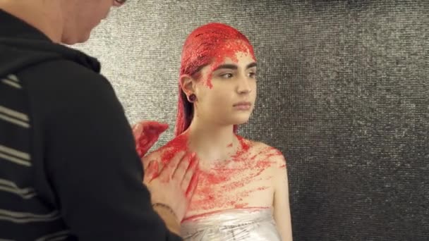 Makeup artist covering girls body with red paint — Stock Video