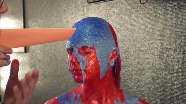 Maquillaje artista que cubre la pintura azul en la cara de las niñas con destellos azules, cámara lenta — Vídeo de stock