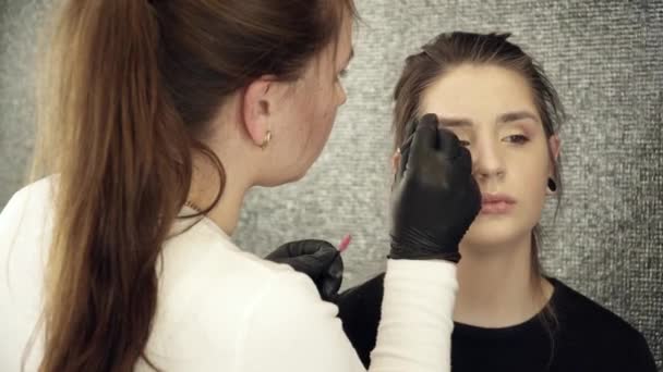 Beautician artist fixing the shape of the right eyebrow in beauty salon — Stock Video