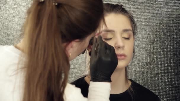 Kosmetolog att göra ögonbrynen för en kvinna — Stockvideo