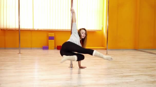 Молодая красивая танцовщица делает трюки с шестом в танцевальном зале — стоковое видео
