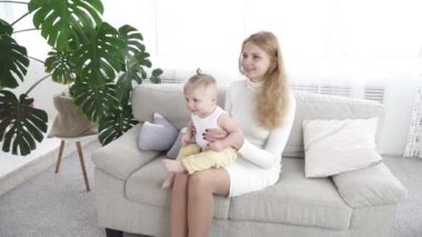 Onun bebek çocuk ile kanepede oturan genç mutlu anne