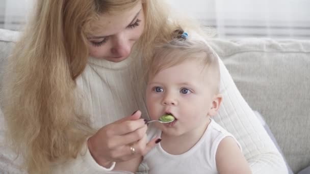 Молодая мать кормит своего маленького мальчика крупным планом — стоковое видео