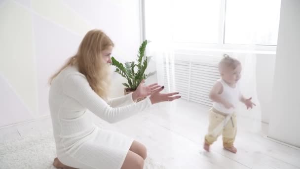 Молодая мама смотрит, как ее маленький мальчик бежит в комнате — стоковое видео