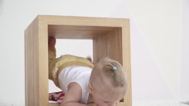 Menino pequeno brincando dentro do cubo de madeira na sala, close-up — Vídeo de Stock