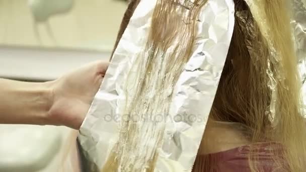 Парикмахер раскрашивает стаи женских волос, крупным планом — стоковое видео