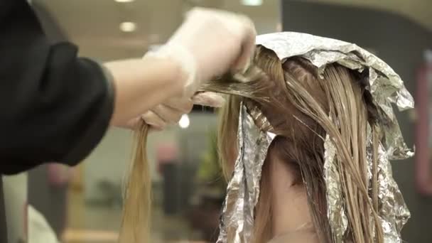 Парикмахер в перчатках раскрашивает светлые волосы в салоне красоты — стоковое видео
