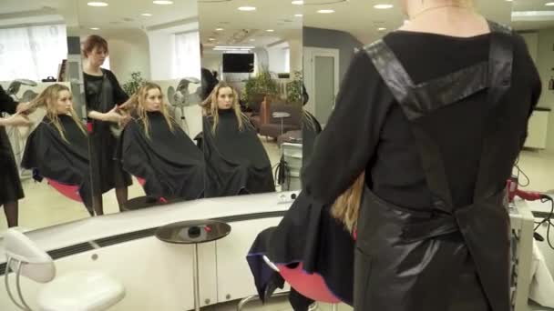 Jovem mulher está tendo corte de cabelo na frente do espelho — Vídeo de Stock