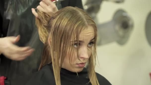 Peluquería está haciendo corte de pelo para una mujer joven — Vídeo de stock