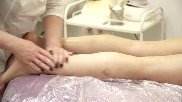 Masajista haciendo masaje de piernas para una mujer en el sofá — Vídeos de Stock