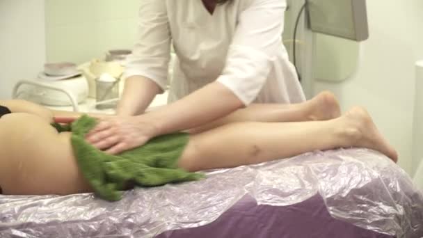 Massagist att göra ben massage för en ung kvinna på soffan, reflektion i spegeln — Stockvideo