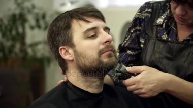 Genç adam salonda, closeup kesmek onun sakalı olan