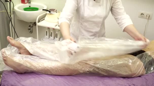Kosmetolog wraping ung kvinna i spasalong — Stockvideo