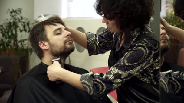 Jovem está tendo sua barba cortada no salão — Vídeo de Stock
