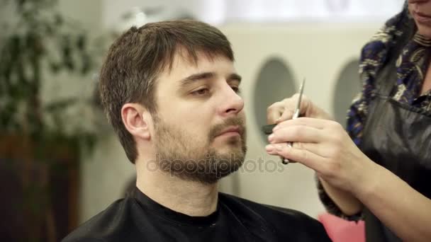 Hairdreser is trimmen jonge mans baard in salon — Stockvideo