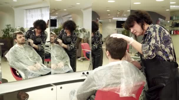 Hairdresser is coloring mans beard in salon — Stock Video