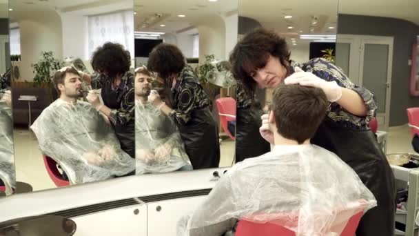 Парикмахер раскрашивает бороду в салоне красоты — стоковое видео