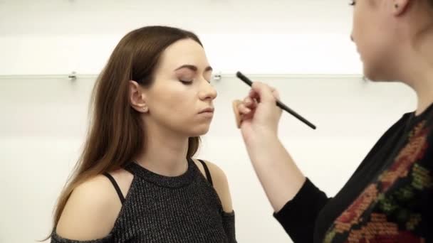 Beautician is applying the eye shadows for a woman — Stock Video