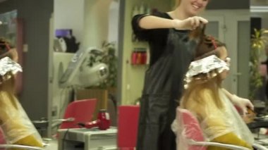 Genç kadın aynanın önünde boyalı saçları geçiriyor