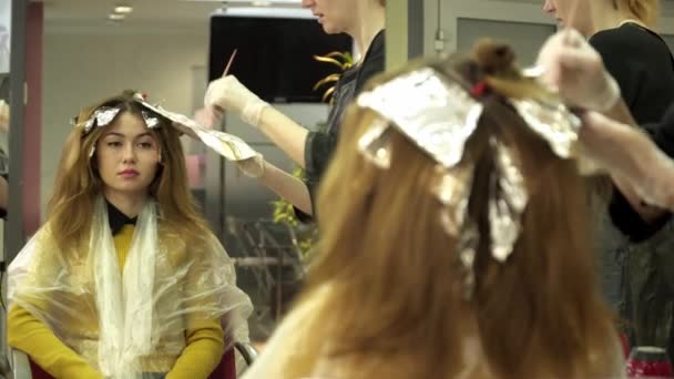 Haarstylist is verven meisjes haar in salon voor de spiegel — Stockvideo