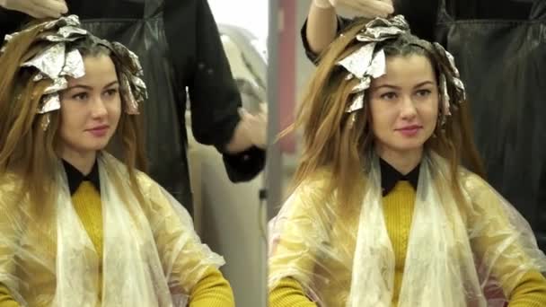 Парикмахер красил девушкам волосы перед зеркалом — стоковое видео