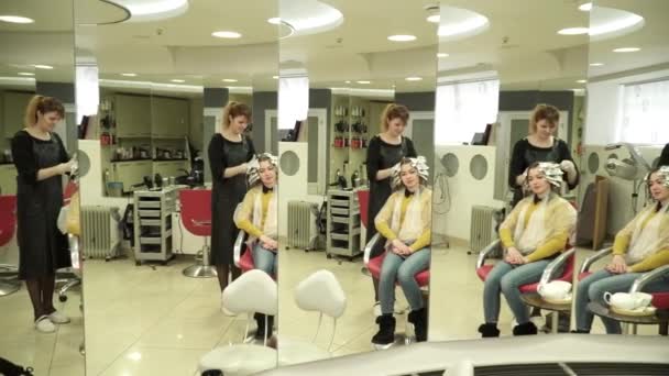 Stylist is dyeing womans hair in front of the mirrors — Stock Video