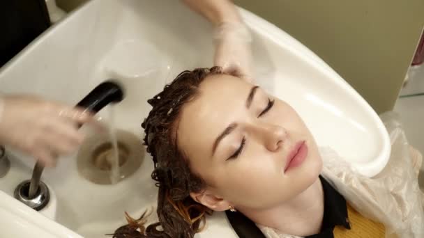 Fryzjer jest mycie młody womans włosów w salonie — Wideo stockowe