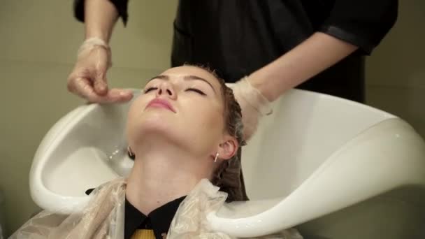 Peluquero está lavando el pelo de las mujeres jóvenes en el salón — Vídeo de stock