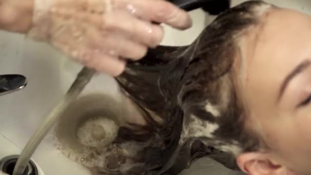 Hair stylist sta lavando i capelli per una giovane donna — Video Stock