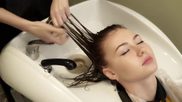 Hair stylist sta lavando i capelli per una giovane donna nel lavandino — Video Stock