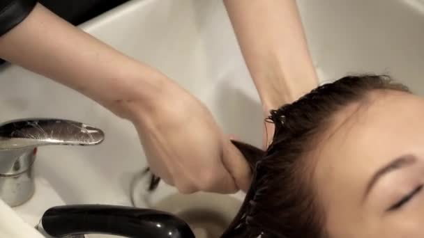 Peluquero está lavando el cabello para una joven hermosa mujer — Vídeos de Stock