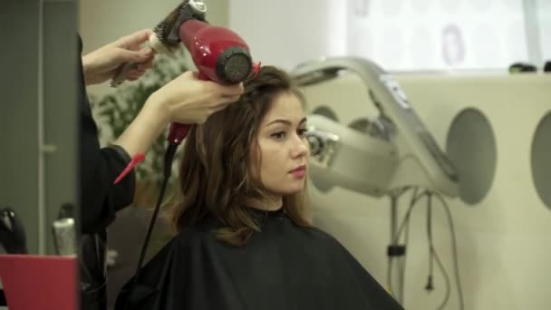 Στυλίστας μαλλιά κάνει κούρεμα για μια νεαρή γυναίκα στο σαλόνι — Αρχείο Βίντεο