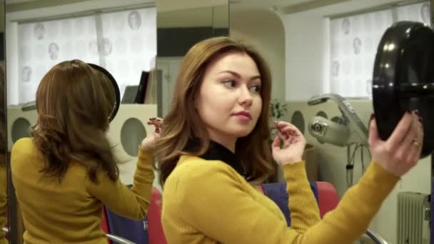 Mujer joven está disfrutando de su hermoso corte de pelo en el espejo — Vídeos de Stock