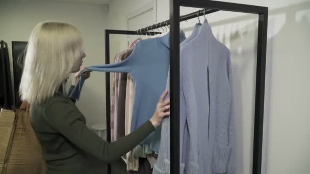 Крупный план молодой женщины, собирающей одежду в бутике — стоковое видео