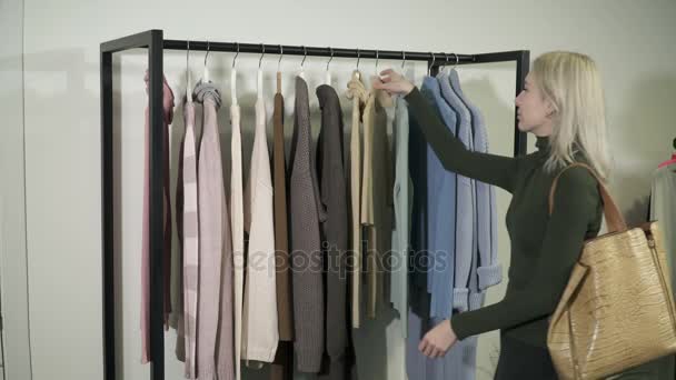 Young woman in boutique selecting new clothes and shocked by the prices — Stock Video