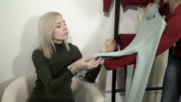 The shop assistant offers the customer new clothes — Stock Video