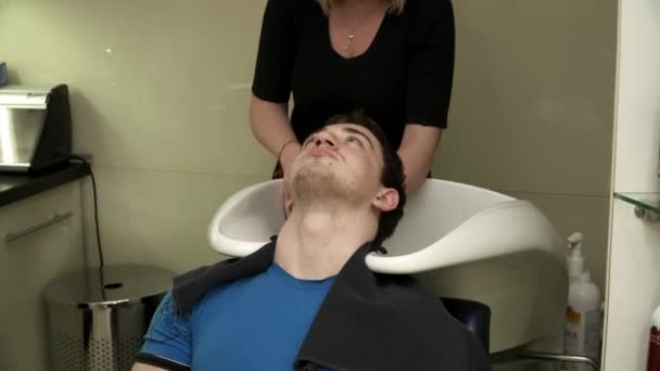 Парикмахер стирает волосы мужчин — стоковое видео