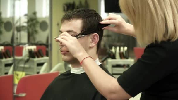 Hairdresser is making a haircut for a man — Stock Video